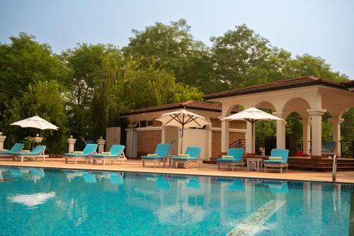 a swimming pool with chairs and umbrellas next to a building at Buddha Maya Garden by KGH Group in Rummindei