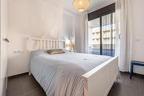 a white bedroom with a large bed and a window at Apartamento La cala in L'Ametlla de Mar