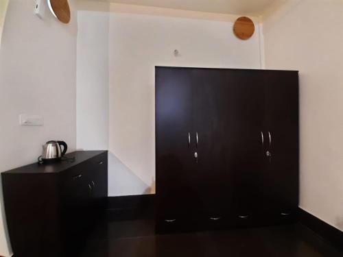 a large black cabinet in a room with white walls at Dzomo Homestay in Gangtok