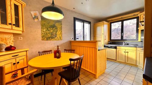une cuisine avec une table et des chaises en bois ainsi qu'une table et des chaises dans l'établissement Gîte Le Pingu - spacieux, calme, plein sud - cabine sauna - 8 personnes, à La Bresse