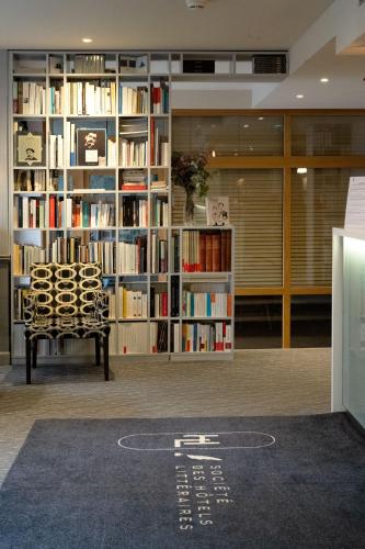 a library with a chair and book shelves with books at Hotel Litteraire Le Swann, BW Premier Collection in Paris