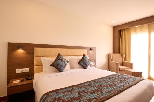 a hotel room with a large bed and a chair at Renest Haridwar in Haridwār