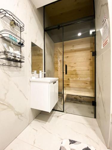 y baño con ducha y lavabo blanco. en Central City Apartments, en Öskemen