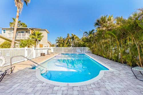 a swimming pool in front of a house with palm trees at Beachy Keen Cottage in Clearwater Beach