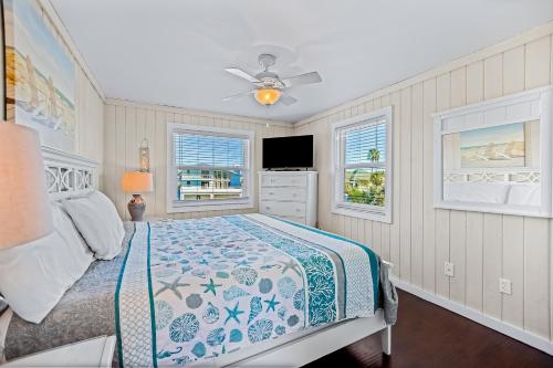 a bedroom with a bed and two windows at Beachy Keen Cottage in Clearwater Beach