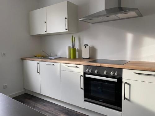 una cocina con armarios blancos y horno negro en Travel Apartments, en Münster