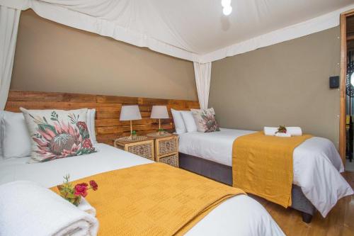 a bedroom with two beds and two tables with flowers at Idwala Le Ingwe Lodge in Hekpoort