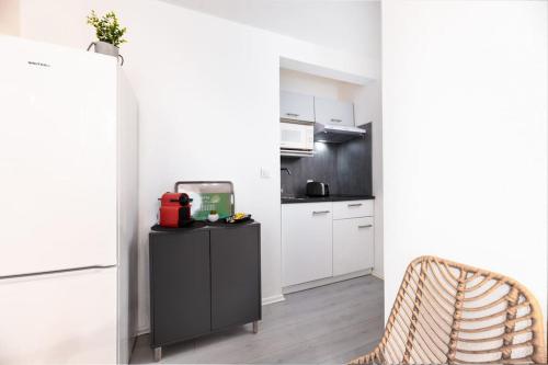 une cuisine avec des armoires blanches et un réfrigérateur noir dans l'établissement L'Alto - Toulousecozyflat - Centre- Parking - Métro, à Toulouse