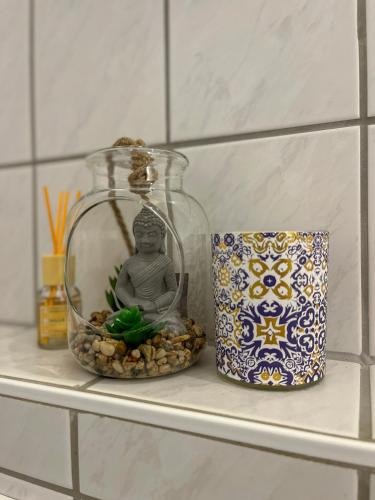 a shelf with a buddha in a glass jar and a candle at Schöne moderne Wohnung Smart Tv in Waldstetten