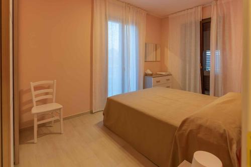 1 dormitorio con 1 cama, 1 silla y 1 ventana en Villa Vimani, en Paestum