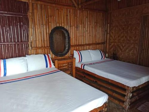 two beds in a room with wooden walls at Jao bay boat charter in Talibon