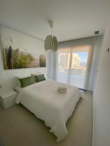 a white bedroom with a large bed and a window at Infinity View SNB in Arenales del Sol