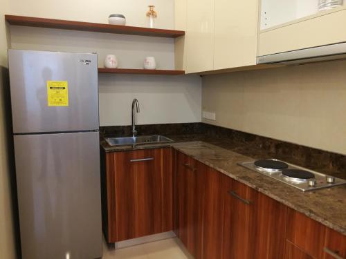 a kitchen with a stainless steel refrigerator and wooden cabinets at Adria Residences - Ruby Garden - 2 Bedroom for 4 person in Manila