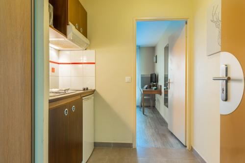 a small kitchen with a door leading into a hallway at Zenitude Hôtel-Résidences Magny-les-Hameaux in Magny-les-Hameaux