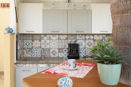 una cocina con armarios blancos y una mesa con una planta en Terra Del Sole, en Macari