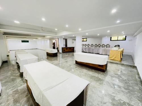 a room with white beds and tables and chairs at Hotel Holiday Pride in Aurangabad