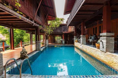 a swimming pool outside of a house with a building at Ruennakornin Homestay in Ban Bang Kho