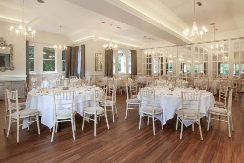 una stanza con tavoli e sedie bianchi e lampadari a braccio di The Dower House Hotel a Woodhall Spa