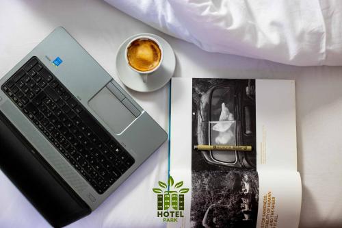 a laptop computer and a cup of coffee on a bed at Hotel Park in Pristina