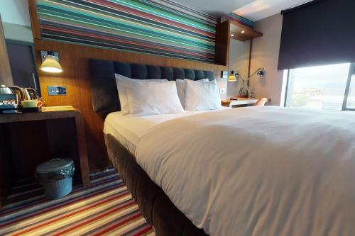 a bedroom with a large white bed with a window at Village Hotel Leeds South in Leeds