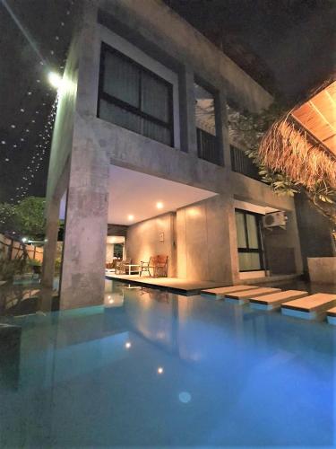 a building with a swimming pool at night at Villa by the Win Pattaya in Jomtien Beach
