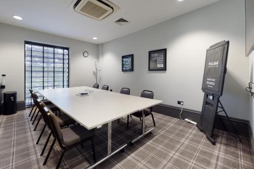 a conference room with a table and chairs and a screen at Village Hotel Leeds South in Leeds