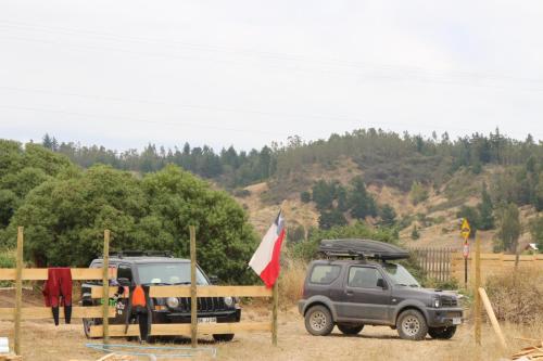 two vehicles parked next to a fence with a flag at Surf and Stay Chile in Navidad