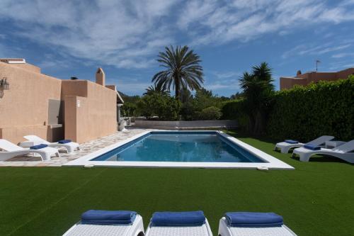 una piscina con sillas de césped y una casa en Villa Simona Ibiza en Ibiza