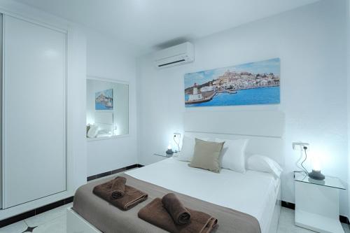 Un dormitorio blanco con una cama con toallas. en Villa Simona Ibiza en Ibiza