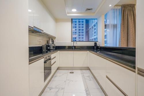 a kitchen with white cabinets and a large window at Primestay - Meera Tower 2BR in Habtoor City in Dubai