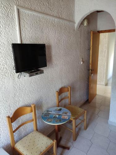 a room with a table and two chairs and a tv at Kissandros Hotel in Agia Galini