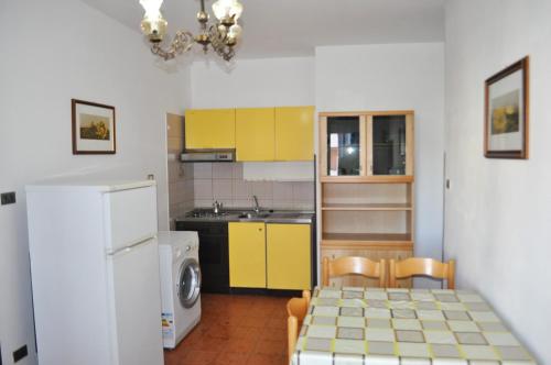 a kitchen with yellow cabinets and a table and a refrigerator at Appartamenti Primula Uno in Silvi Marina