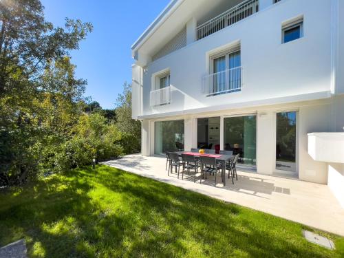 una grande casa bianca con patio e prato di Esclusiva Villa Frontemare in Tana della Volpe 2 a Lignano Sabbiadoro