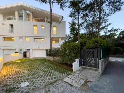 un edificio bianco con un cancello davanti di Esclusiva Villa Frontemare in Tana della Volpe 2 a Lignano Sabbiadoro
