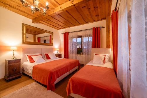 a bedroom with two beds with red curtains and a mirror at RetroHouse in Reda