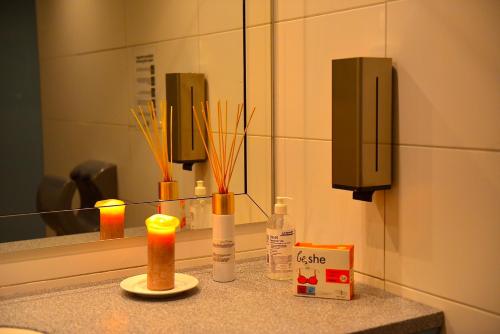 ein Waschbecken mit Spiegel und Kerzen auf der Theke in der Unterkunft Hotel Zum Forst in Kranzberg