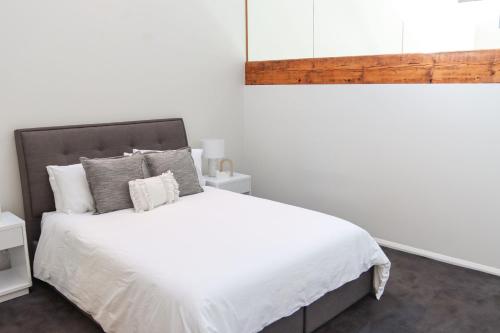 a bedroom with a white bed with white sheets and pillows at Bendigo Townhouse - Walk to the CBD in Bendigo