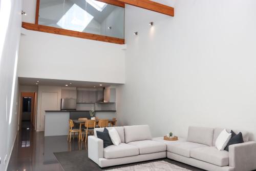 a living room with two white couches and a kitchen at Bendigo Townhouse - Walk to the CBD in Bendigo
