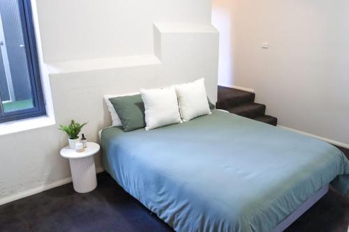 a small bedroom with a bed with blue sheets and pillows at Bendigo Townhouse - Walk to the CBD in Bendigo