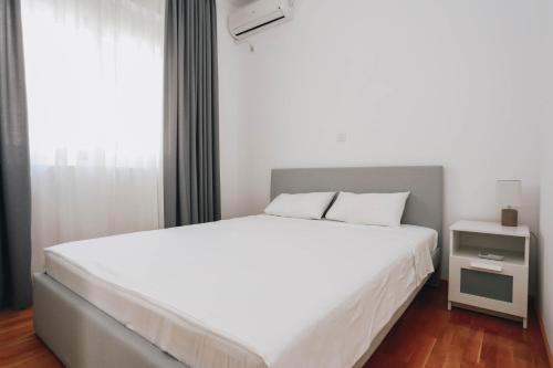 a bedroom with a large white bed and a window at Sunny Side apartment in Bečići