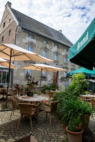 a patio with tables and umbrellas in front of a building at Hotel De Oude Brouwerij in Mechelen