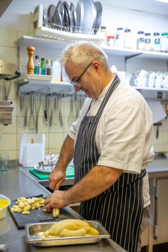 a man in a kitchen preparing food on a counter at Hotel De Oude Brouwerij in Mechelen
