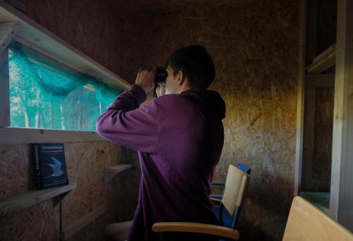 Une femme qui parle sur un téléphone portable qui regarde par une fenêtre dans l'établissement Bear Watching Hide of Alutaguse, à Palasi