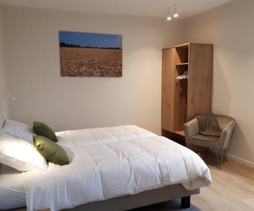 a bedroom with a white bed and a chair at Fluithoekhoeve in Koksijde