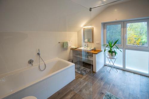 ein weißes Bad mit einer Badewanne, einem Waschbecken und einem Fenster in der Unterkunft Alte Mühle Hotel & Restaurant in Rödental
