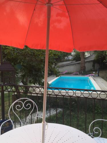 a red umbrella sitting on a table next to a pool at Maison d'Hôtes La Bastide Bleue in Marseille