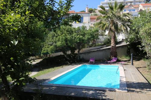 a swimming pool in a garden with two chairs and a palm tree at Maison d'Hôtes La Bastide Bleue in Marseille