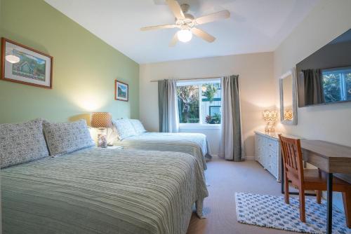 a bedroom with two beds and a desk and a window at Regency at Poipu Kai #914 in Koloa