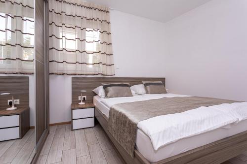 a bedroom with a large bed and two night stands at Apartments Crnekovic Tomislava 8 in Baška