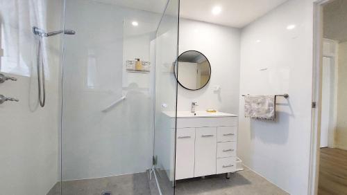 a bathroom with a shower and a sink and a mirror at Swan Place In The Heart of Kiama in Kiama